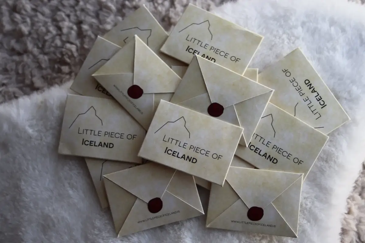 A pile of Little piece of Iceland cards and envelopes, each closed with a red seal, on white sheepskin
