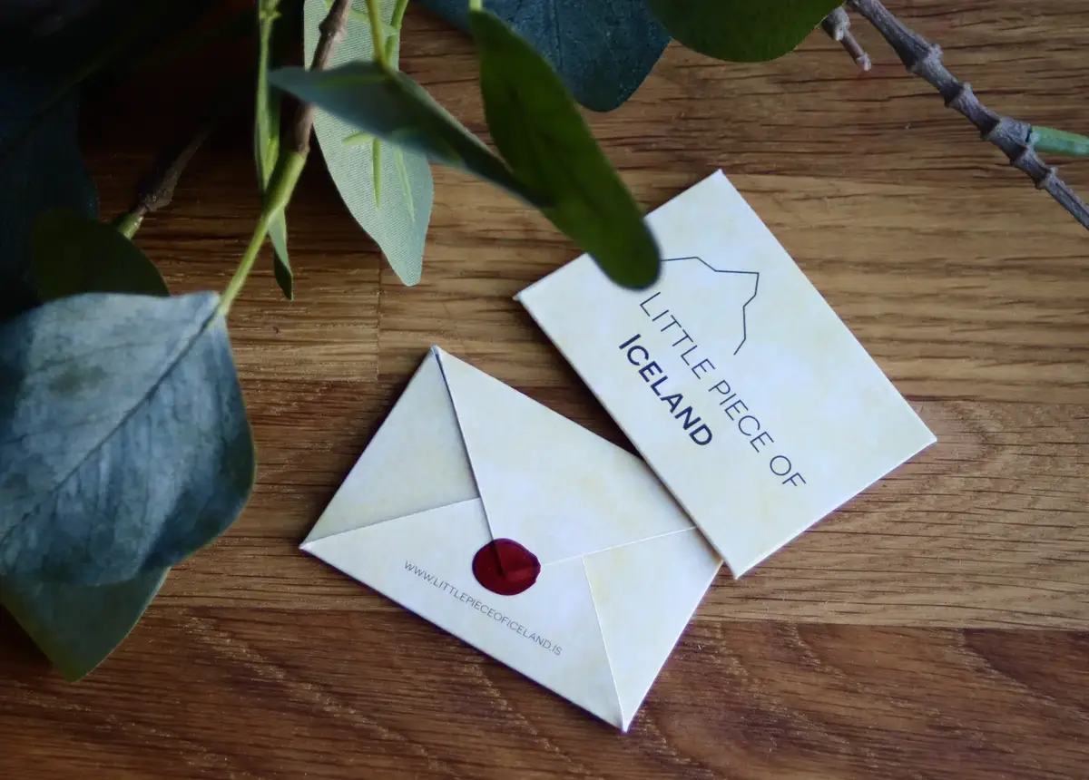 A Little piece of Iceland card and an envelope closed with a red seal on a wooden table under eucalyptus leaves